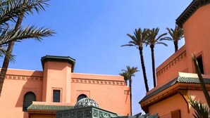 Un bâtiment doté d’un dôme et de fenêtres en arc de cercle, entouré de palmiers.