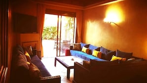 A living room with a sofa, a coffee table, and a TV mounted on the wall. - Palmeraie Village 609 (Marrakech)