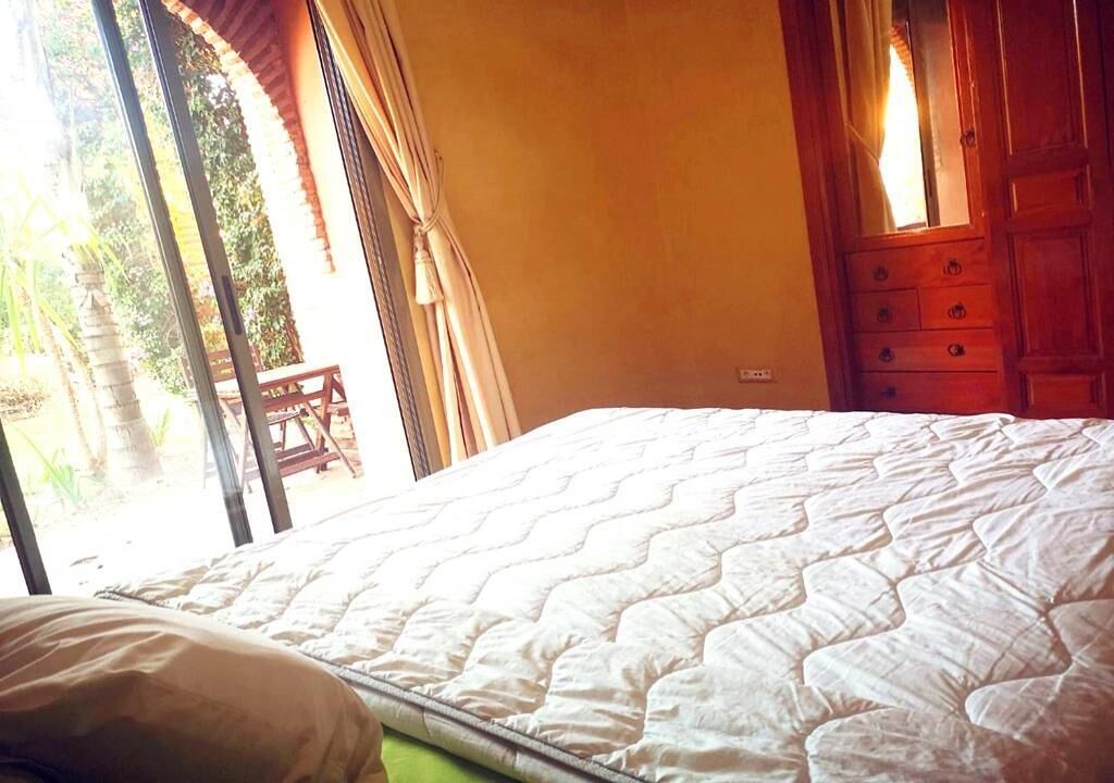 A bedroom with a bed, a wooden dresser, and a window with curtains.