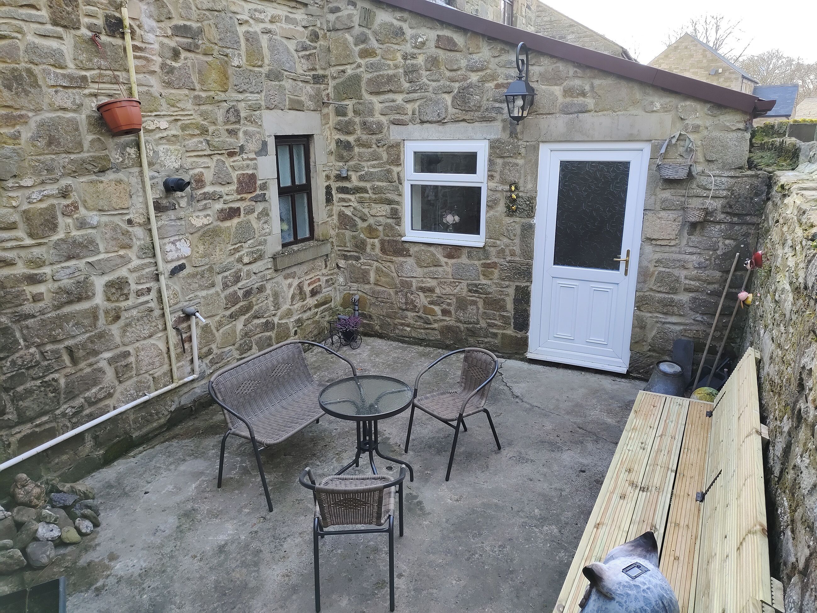 A stone building with a door, windows, and a small table with chairs.