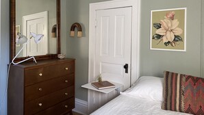 A bedroom with a dresser, a bedside table, a bed, a door, a mirror, and a floral painting on the wall. - Eclectic Home Near UWM Campus and Lake Michigan (Shorewood)