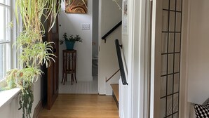 A wooden staircase with a black handrail, white walls, and a door with a grid pattern. - Eclectic Home Near UWM Campus and Lake Michigan (Shorewood)