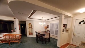 A dining area with a table and chairs, a bench, and a chandelier. - Cottage at Chimney Ridge Farms (Duncansville)