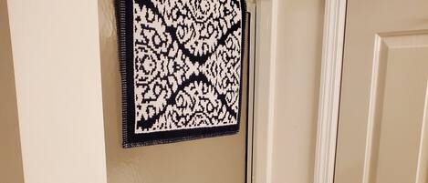 A bathroom with a shower door, a towel rack with a patterned towel, and a door with a brass handle.