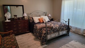 A bedroom with a bed, dresser, mirror, and window. - Cottage at Chimney Ridge Farms (Duncansville)