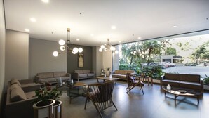 Ein modernes Wohnzimmer mit Sofas, Sesseln und einem Couchtisch. Üchtisgefäße und ein großes Fenster mit Blick auf die Straße.