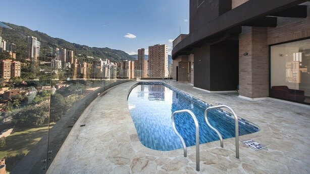 Ein Dachpool mit freiem Blick auf umliegende Gebäude und eine hügelige Landschaft.