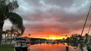 Un port de plaisance avec des bateaux amarrés, une étendue d’eau calme et un coucher de soleil en arrière-plan.