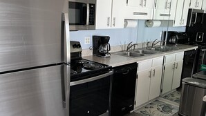 Una cocina moderna con electrodomésticos de acero inoxidable, armarios blancos y piso de madera.