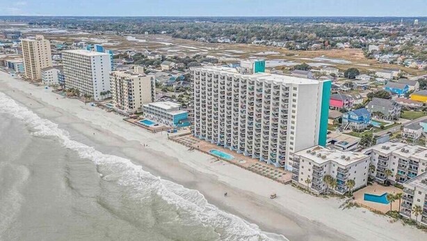Un hotel costero con varios edificios altos, una playa y vista al océano.