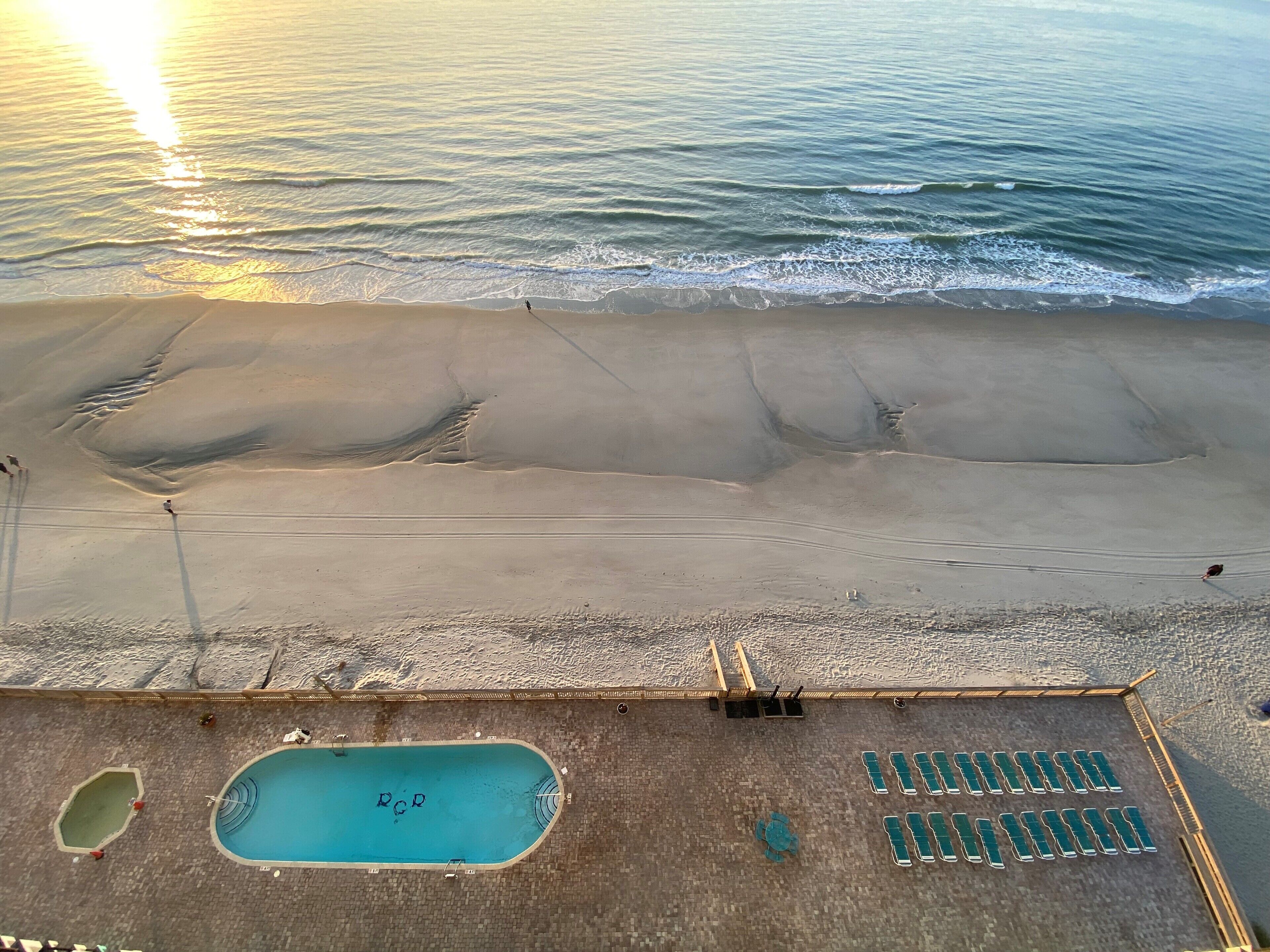 Blick auf einen Strand mit Pool und Liegestühlen.