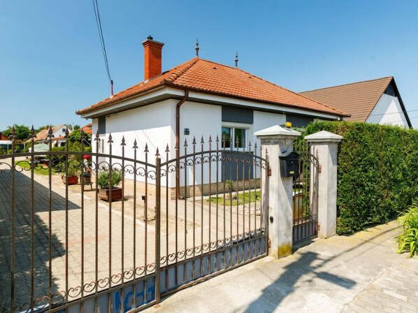 A house with a tiled roof, a fenced yard, and a mailbox.