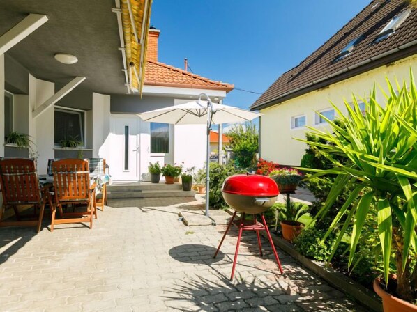 Un patio con una parrilla, mobiliario exterior y plantas en macetas.
