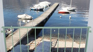 Una marina con barcos amarrados, un muelle que se adentra en aguas tranquilas y montañas al fondo.