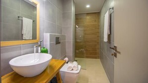 A modern bathroom with a large white sink, a wooden vanity, a mirror, a towel rack, and a glass-enclosed shower area. - Immaculate 1-Bed House in Zakynthos (Zakynthos)