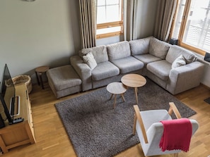 A modern living room with a sectional sofa, a small round table, a grey rug, and a wooden floor. - Alppinuppu by Interhome (Nilsiä)