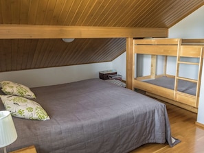 A bedroom with a bunk bed, a single bed, and a nightstand with a lamp. - Alppinuppu by Interhome (Nilsiä)