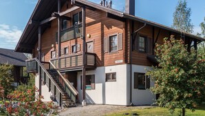 A two-story building with a wooden facade, a balcony, and a staircase leading to the entrance. - Alppinuppu by Interhome (Nilsiä)