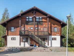 A two-story wooden building with a balcony and a staircase leading to the upper floor. - Alppinuppu by Interhome (Nilsiä)