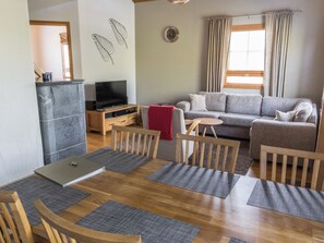 Una sala de estar con sofá, televisor y comedor con mesa y sillas.