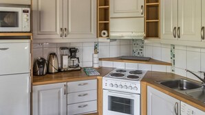 A compact kitchen with white cabinets, a built-in microwave, a coffee maker, and a stove. - Alppinuppu by Interhome (Nilsiä)