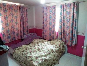 Cozy retreat with a single bed, floral-patterned bedspread, and a door leading to more space.