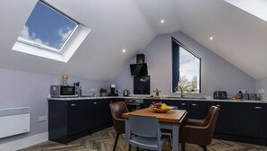 Una cucina moderna con mobili scuri, un tavolo da pranzo in legno e un'ampia finestra a lucernario.