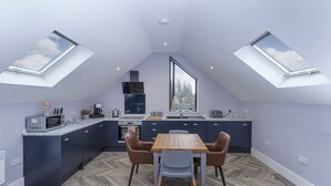 Una cucina moderna con zona pranzo, lucernari e un'ampia finestra.