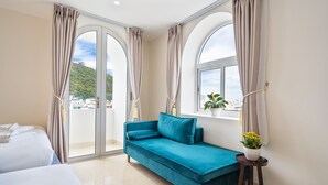 A hotel room with a teal sofa, a bed, and a window with curtains. - Aquatel Vung Tau (Ho Chi Minh City)