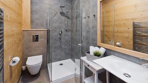 A modern bathroom with a glass-enclosed shower, a white toilet, and a large mirror with a wooden frame. - Lipki Park Resort by Interhome (Zakopane)