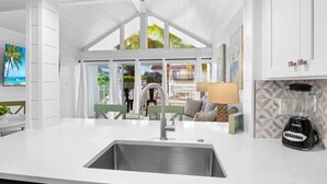 A modern kitchen with a large island, white cabinetry, and a view of the outdoors. - Beach Condo with Pool Near Holmes Beach! (Holmes Beach)