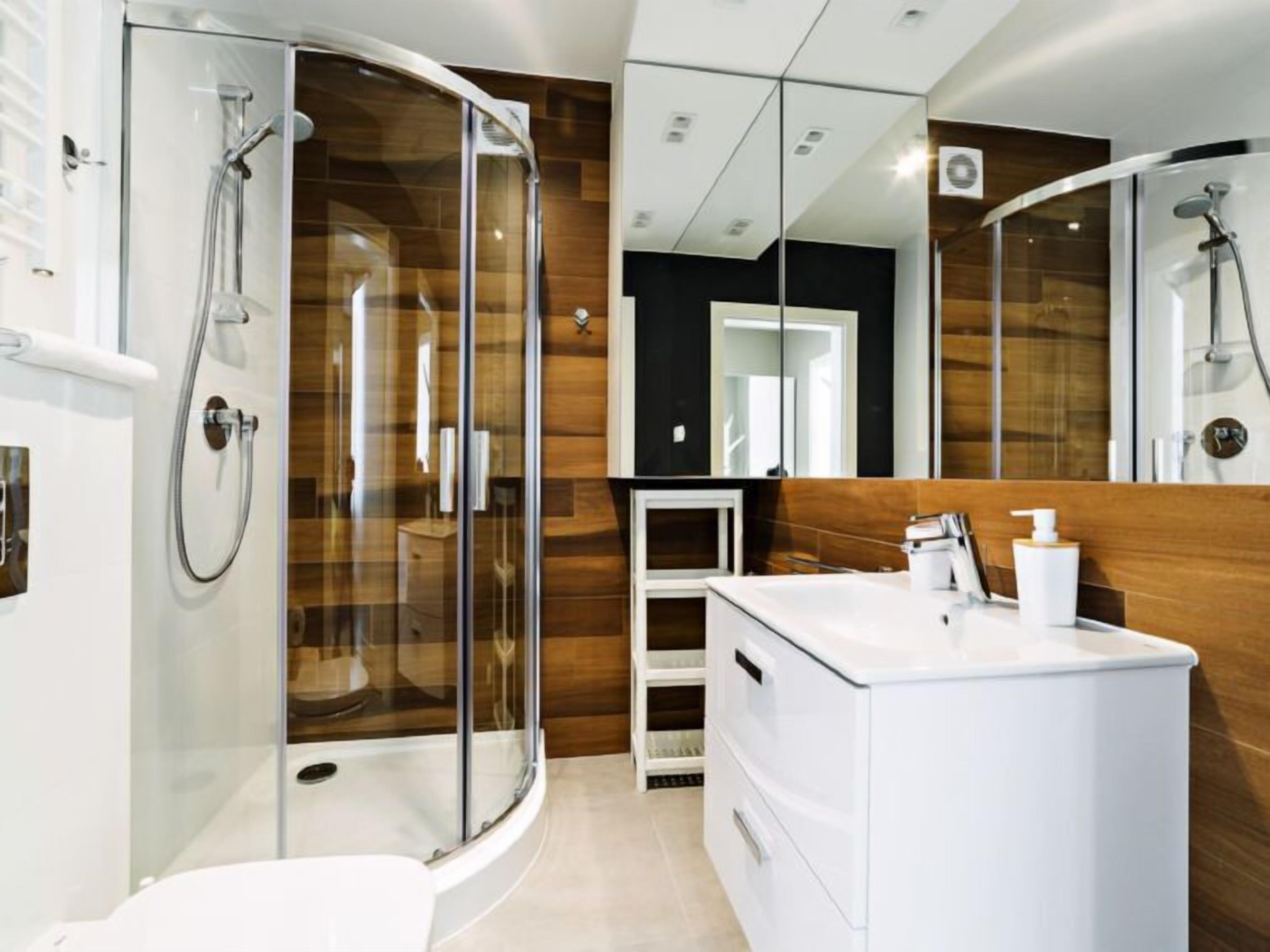 Une salle de bain moderne avec une douche à parois de verre, un meuble-lavabo blanc et un grand miroir.