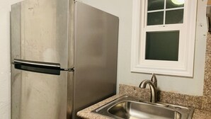 Una cocina con refrigerador de acero inoxidable, encimera de granito y ventana sobre el fregadero.