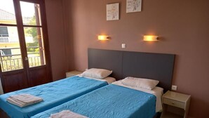 Une chambre avec deux lits, chacun recouvert d’une courtepointe bleue et agrémenté d’oreillers blancs, et une table de chevet dotée d’un tiroir.