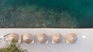 An aerial view of a beachside hotel with a row of sun loungers and umbrellas. - Hotel Milna (Milna)