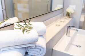 A bathroom with a white bathtub, a mirror, and a towel rack with folded towels and a sprig of rosemary. - Hotel Milna (Milna)