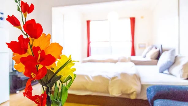 A hotel room with a bed, a sofa, and a vase of flowers. - Commence3 (Sapporo)