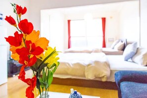 A hotel room with a bed, a sofa, and a vase of flowers. - Commence3 (Sapporo)