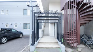 A gated entrance with steps leading to a building, a parked car, and bicycles. - Commence3 (Sapporo)