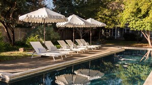 Uma área à beira da piscina com espreguiçadeiras e guarda-sóis.