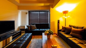 A modern living room with a flat-screen TV, two sofas, a coffee table with flowers, and a standing lamp. - Prime (Sapporo)