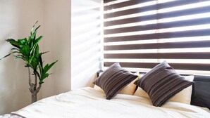 A bedroom with a bed, two pillows, and a potted plant. - Prime (Sapporo)