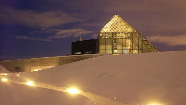 A snow-covered landscape with a pyramid-shaped building illuminated at night. - Prime (Sapporo)