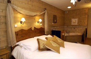 Ein Zimmer mit Holzwänden, einem Bett, zwei Wandlampen und einem Badezimmer mit einer Badewanne.