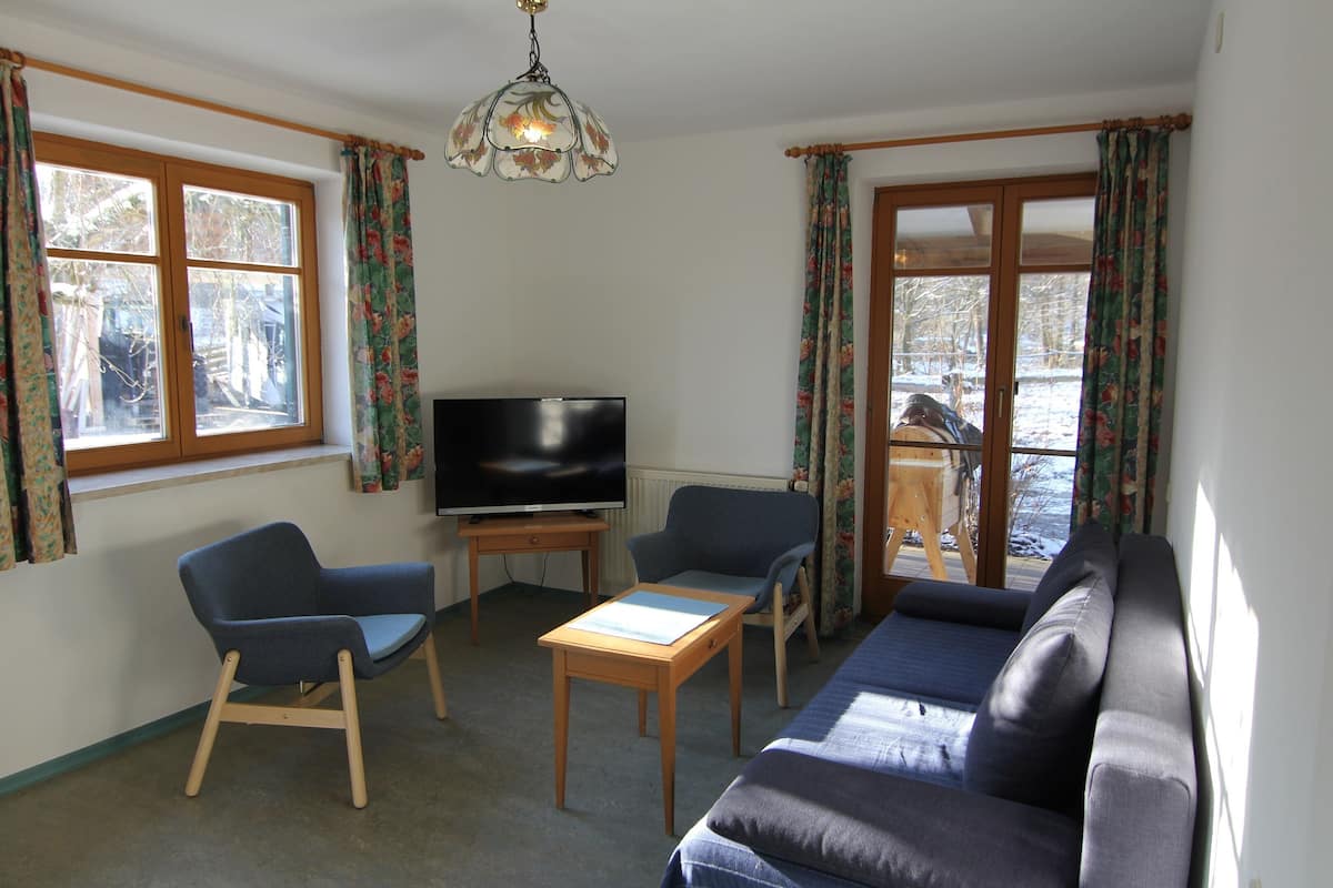 A living room with a sofa, two chairs, a television, and a table.