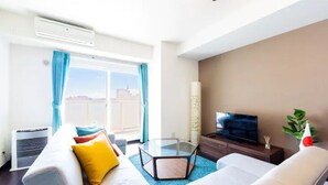 A modern living room with a sofa, a glass coffee table, a flat-screen TV, and a large window with curtains. - Fancy (Sapporo)