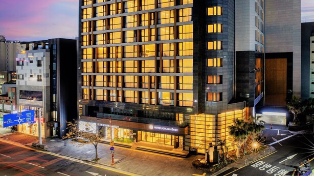 A modern hotel with a grid of windows, a ground-level entrance, and a visible sign for 'Hotel Golden Daisy'. - Hotel Golden Daisy Seogwipo Ocean (Seogwipo)