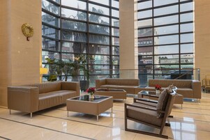 A spacious lobby with large windows, leather sofas, and a coffee table.