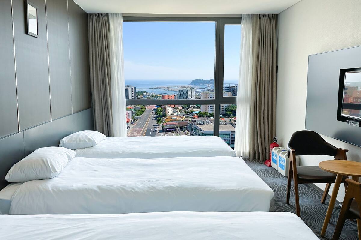A hotel room with two beds, a TV, a small table, and a chair.