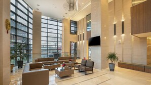 A spacious lobby with large windows, a flat-screen TV, and modern furniture. - Hotel Golden Daisy Seogwipo Ocean (Seogwipo)